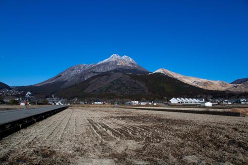 a mountain in the distance with a dirt road in the foreground at Yufuin Lamp no Yado in Yufuin