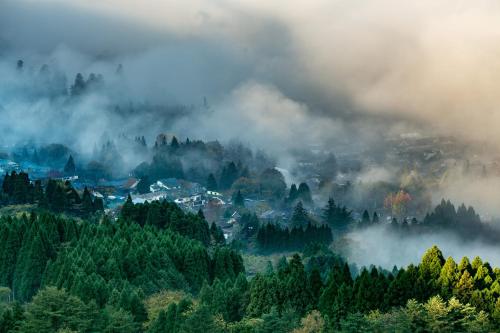 a town in the middle of a forest with clouds at Yufuin Lamp no Yado in Yufuin