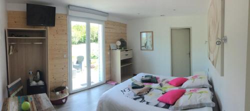 een slaapkamer met een groot bed met roze kussens bij Chambres d'hôtes de L'orval in Thiergeville
