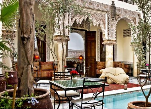 un vestíbulo con piscina, mesas y árboles en Riad Al Loune, en Marrakech