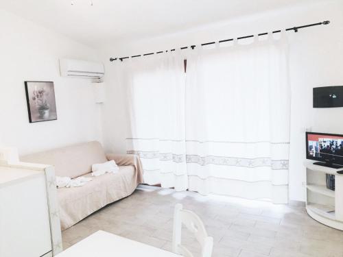a white living room with a couch and a window at Marineledda Apartments in Golfo Aranci
