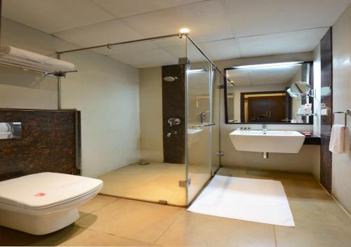 a bathroom with a shower and a toilet and a sink at Green View Clarks Inn, Shimoga in Shimoga