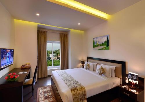 a hotel room with a large bed and a window at Green View Clarks Inn, Shimoga in Shimoga