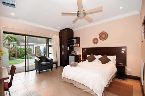 a bedroom with a large bed with a ceiling fan at Africa Beach B&B in Port Elizabeth