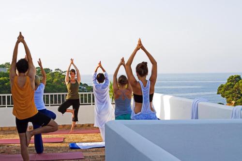 a group of people doing yoga on a ledge at Hotel Apartamentos Cala Santanyi in Cala Santanyi
