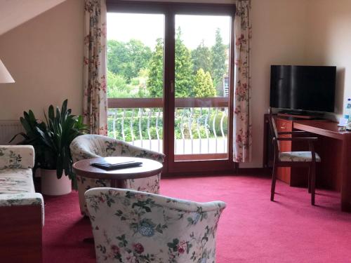 a living room with chairs and a tv and a window at Hotel Erfurtblick in Erfurt