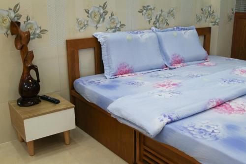 a bed with blue sheets and pink flowers on it at Nature House Homestay in Ho Chi Minh City