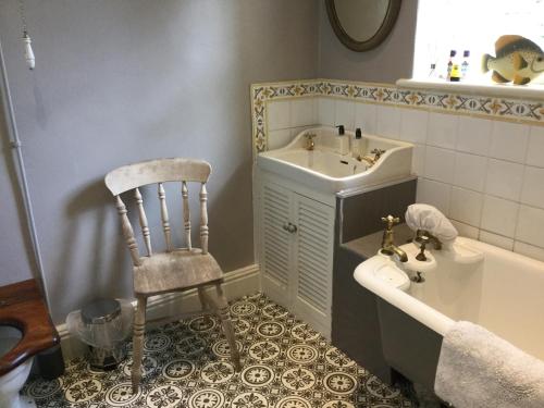 uma casa de banho com uma cadeira, um lavatório e uma banheira em Braeside em Alnwick