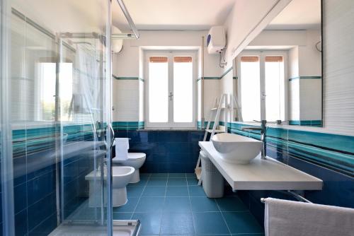 Baño azul con 2 lavabos y 2 aseos en Villa Orrì, en Tortolì