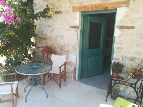 a patio with a table and chairs and a green door at Kritikies Lasea in Pitsidia