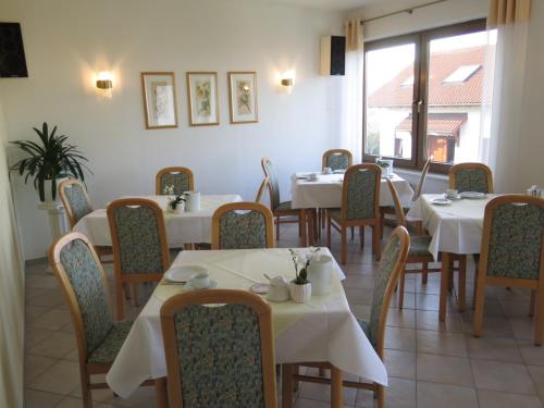 un restaurante con mesas y sillas blancas y una ventana en Hotel Erfurtblick, en Erfurt