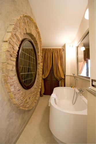 a bathroom with a bath tub and a round mirror at Donna Camilla Savelli - VRetreats in Rome