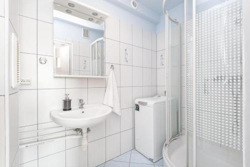 a white bathroom with a sink and a shower at Rooms4Less in Gdańsk
