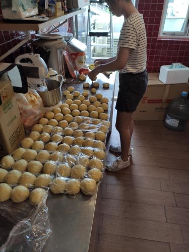 a woman standing in a bakery with a pile of bread at mydeer backpacker in Tainan