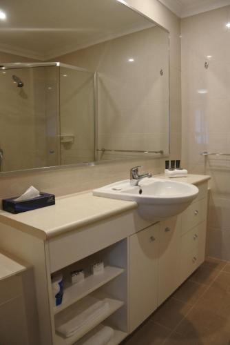 a bathroom with a sink and a large mirror at Bunbury Hotel Koombana Bay in Bunbury