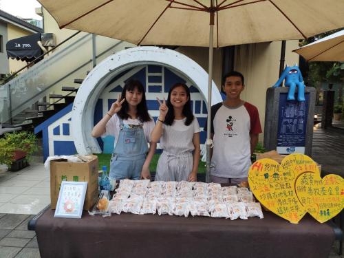three people standing in front of a table with food at mydeer backpacker in Tainan