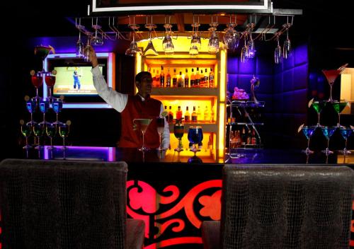 a bartender standing behind a bar with a drink at M B Greens Clarks Inn in Morādābād