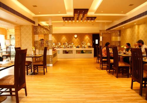 a restaurant with people sitting at tables in a room at M B Greens Clarks Inn in Morādābād