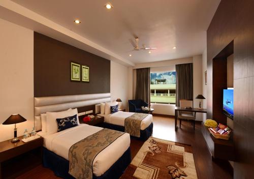 Cette chambre comprend deux lits et une télévision. dans l'établissement M B Greens Clarks Inn, à Moradabad