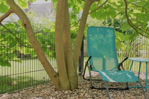 a blue chair and a table next to a tree at Susanne Hendus in Neustadt in Holstein