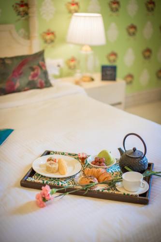 a tray with food and a tea set on a bed at Rose Amer in Jaipur
