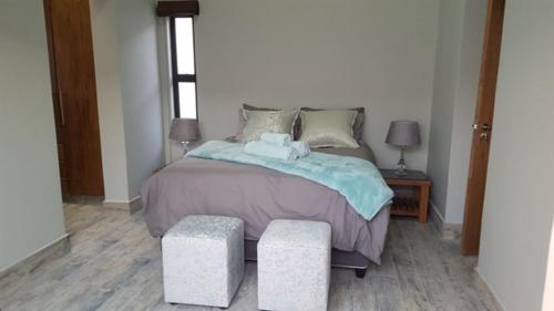 a bedroom with a bed with two stools next to it at Sunset Lagoon in Port Nolloth