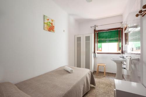 a white bedroom with a bed and a sink at Hostal Las Nieves in Ibiza Town