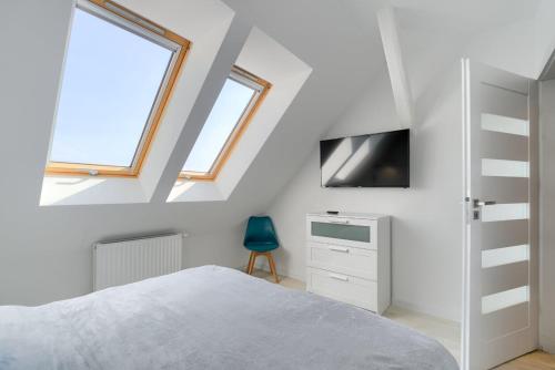 a white bedroom with a bed and a tv at Apartament 444 Apartamenty No.1 in Szczecin
