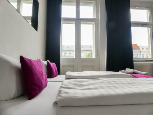 two beds in a room with two windows at Goldmarie in Berlin