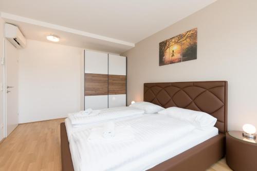 una camera da letto con un grande letto con lenzuola bianche di Yourapartment Prater a Vienna