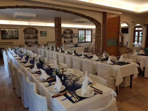 Un gran salón de banquetes con mesas y sillas blancas. en Albergo Ristorante Bergallo, en Tovo San Giacomo