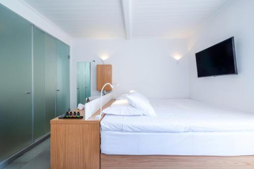 a bedroom with a white bed and a tv at Dreambox Mini Villas in Ornos