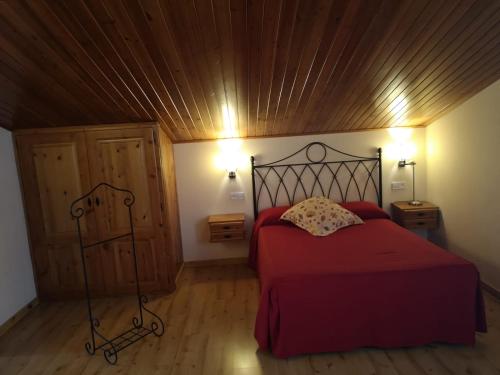 a bedroom with a red bed and a wooden ceiling at Hostal Cal Franciscó in Gósol
