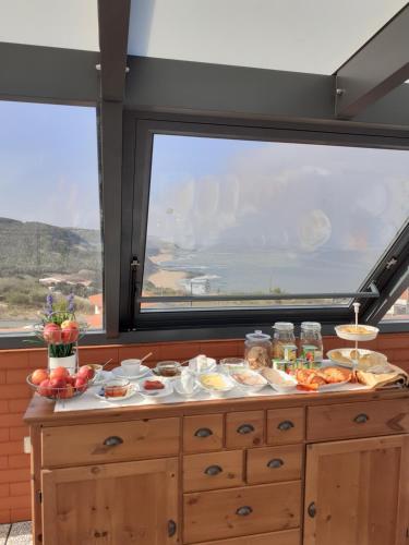 un buffet de nourriture sur une table devant une fenêtre dans l'établissement Casa das Barcas, à Lourinhã