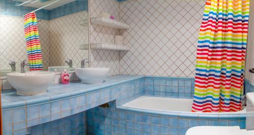 La salle de bains est pourvue de 2 lavabos et d'un rideau de douche coloré. dans l'établissement El Chalet del Pinar, à Cuenca