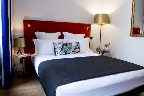 a bedroom with a large bed with a red headboard at Hôtel Cardinal Bordeaux Centre in Bordeaux