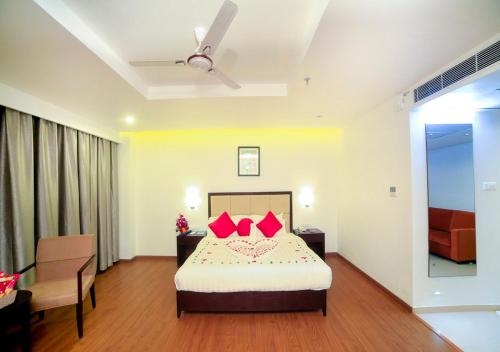 a bedroom with a bed with red pillows at Triguna Clarks Inn Kurnool in Kurnool
