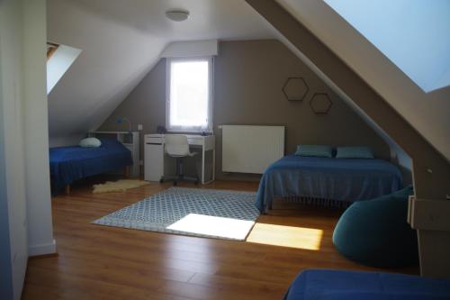 Cette chambre mansardée comprend deux lits et un bureau. dans l'établissement Gîte la Briantaise, à Saint-Malo