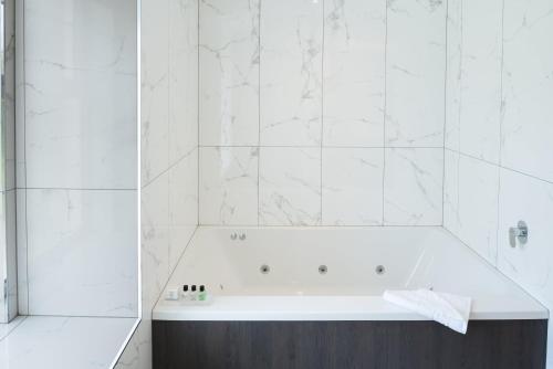 a white bathroom with a tub and a shower at Dalmeny Park House Hotel in Barrhead