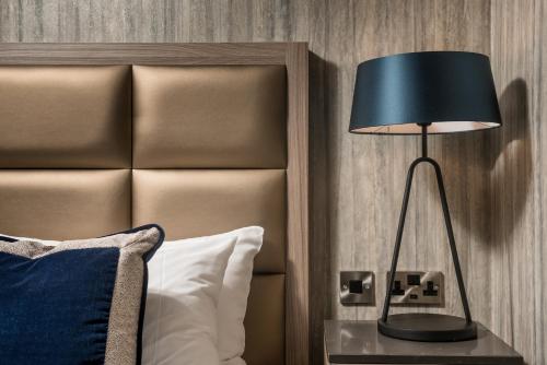 a black lamp on a table next to a bed at Dalmeny Park House Hotel in Barrhead