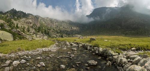 a river in a field with rocks and a mountain at Ca’d’ambra in Groscavallo