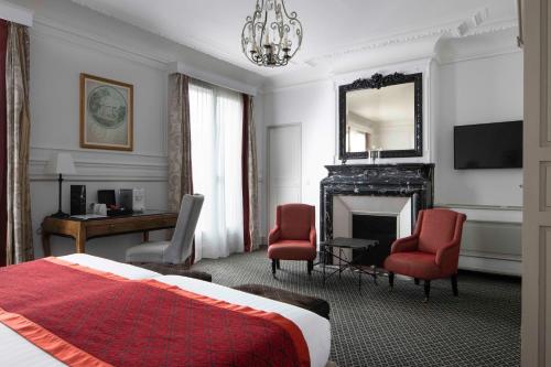 een slaapkamer met een bed, een bureau en een open haard bij Bradford Elysées - Astotel in Parijs