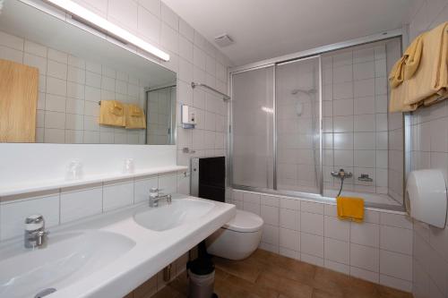 a white bathroom with a sink and a toilet at Hotel de Moiry Supérieur in Grimentz