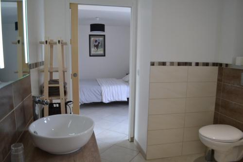 a bathroom with a sink and a toilet and a bed at Le Paddock des Caloges in Le Tilleul
