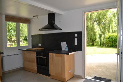 d'une cuisine avec cuisinière et d'une porte donnant sur une cour. dans l'établissement Le Paddock des Caloges, au Tilleul