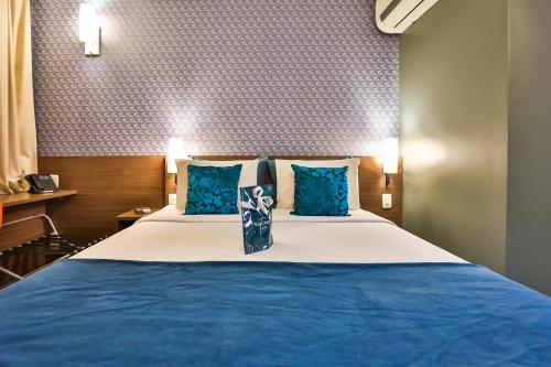 a bedroom with a large bed with blue pillows at San Diego Express Barro Preto in Belo Horizonte