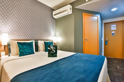 a bedroom with a large bed with blue pillows at San Diego Express Barro Preto in Belo Horizonte