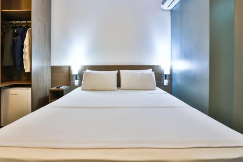 a bedroom with a large bed with white sheets at San Diego Express Barro Preto in Belo Horizonte