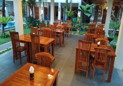 an empty restaurant with wooden tables and chairs at Swan Inn in Ubud