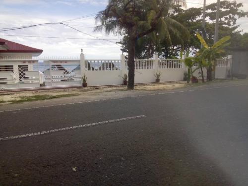 a street with a white fence and a tree at LUNA OSLOB TRAVELLERS INN - Beach Front in Oslob